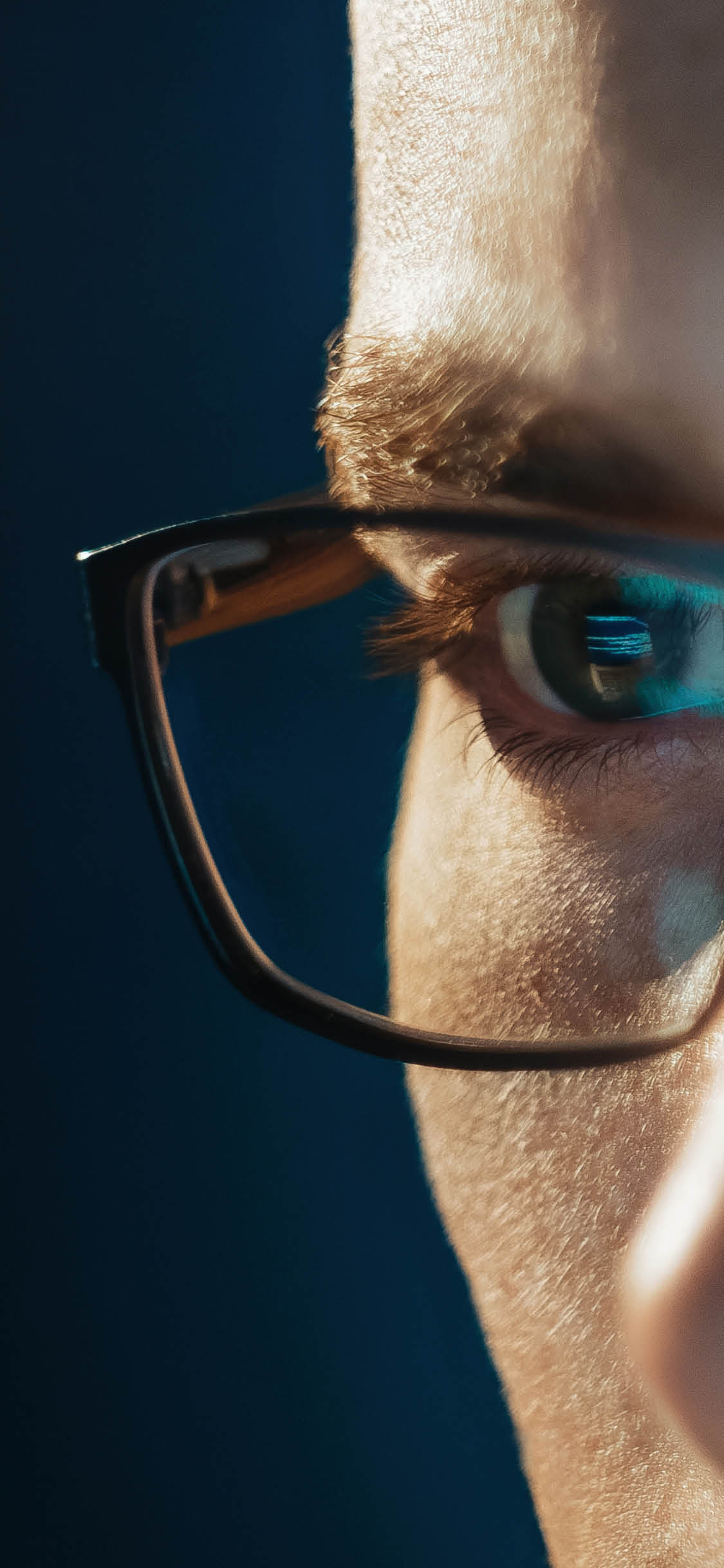 Close-up portrait of focused software engineer wearing eyeglasses looking at computer screen working with big data. Programming code reflecting in glasses. Data science, Machine Learning, AI concept