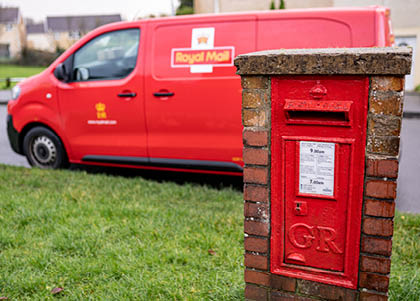 Red vintage mailbox for letters and Royal Mail van, British postal service and courier company